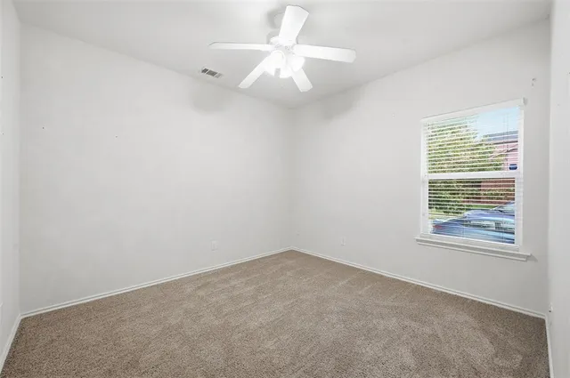 an empty room with a window and a fan