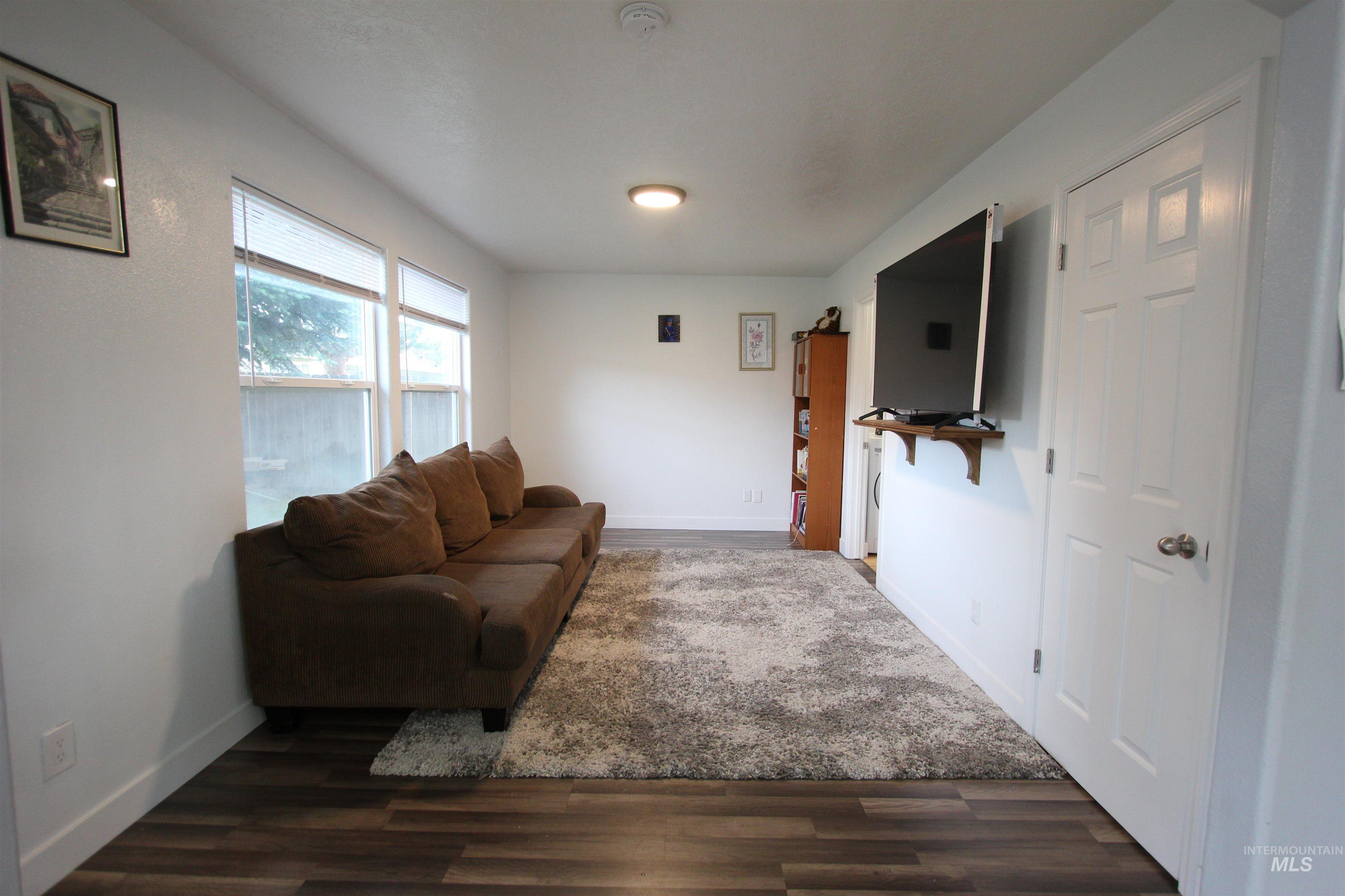 4816 Kadie Street Caldwell, ID 83607 - Photo 12 of 23 Living area featuring wood-finish flooring, multiple windows providing natural light, white baseboards, and a white paneled door