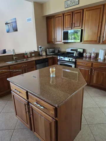 a kitchen with granite countertop a refrigerator and a sink