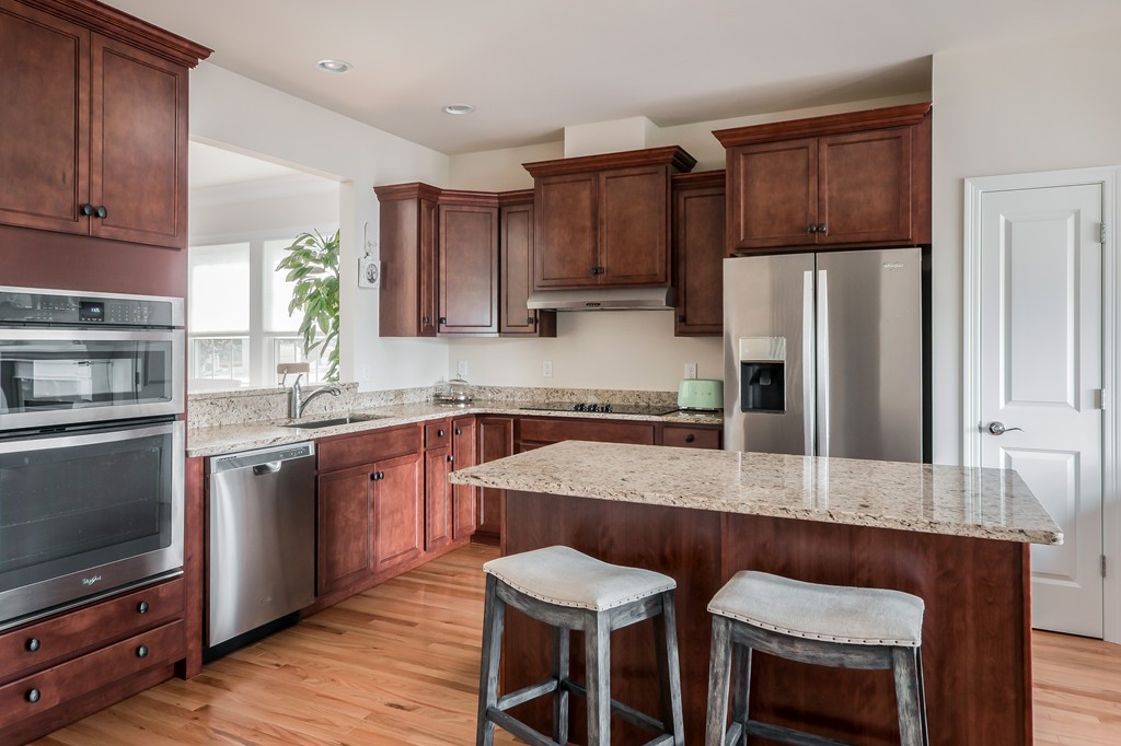81 Monroe Drive, Unit 16 Holliston, MA 01746 - Photo 15 of 30 a kitchen with stainless steel appliances granite countertop a table chairs microwave and refrigerator