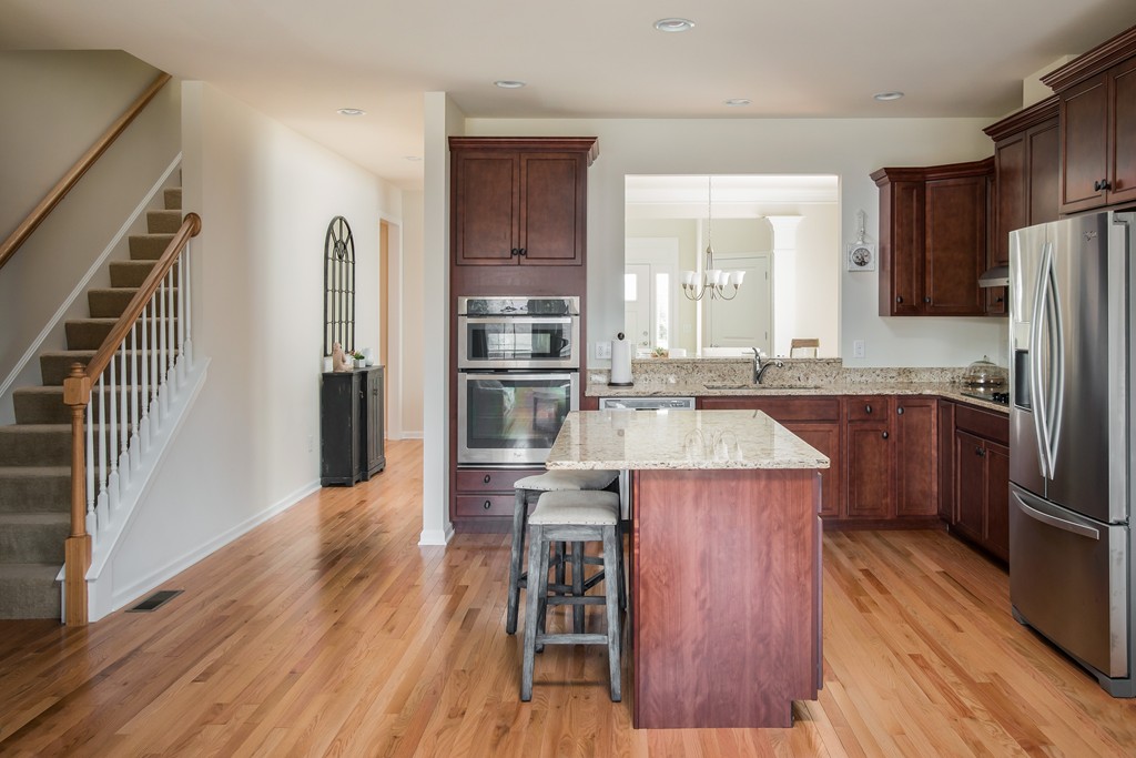 81 Monroe Drive, Unit 16 Holliston, MA 01746 - Photo 16 of 30 a kitchen with kitchen island wooden floors and stainless steel appliances