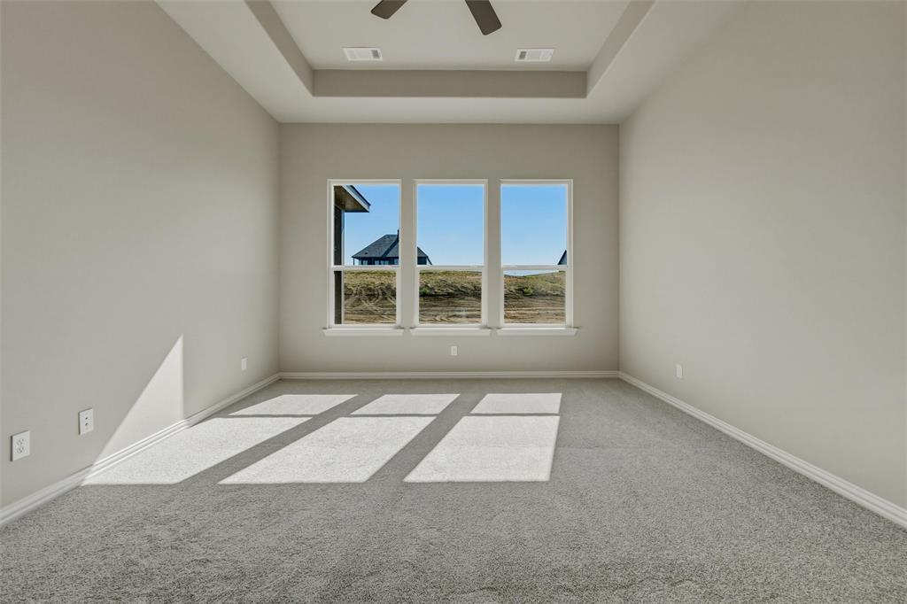 153 Big Sky Road Decatur, TX 76234 - Photo 20 of 38 Tray ceiling with a ceiling fan, light gray wall paint, three large windows, white window trim, and gray carpet flooring