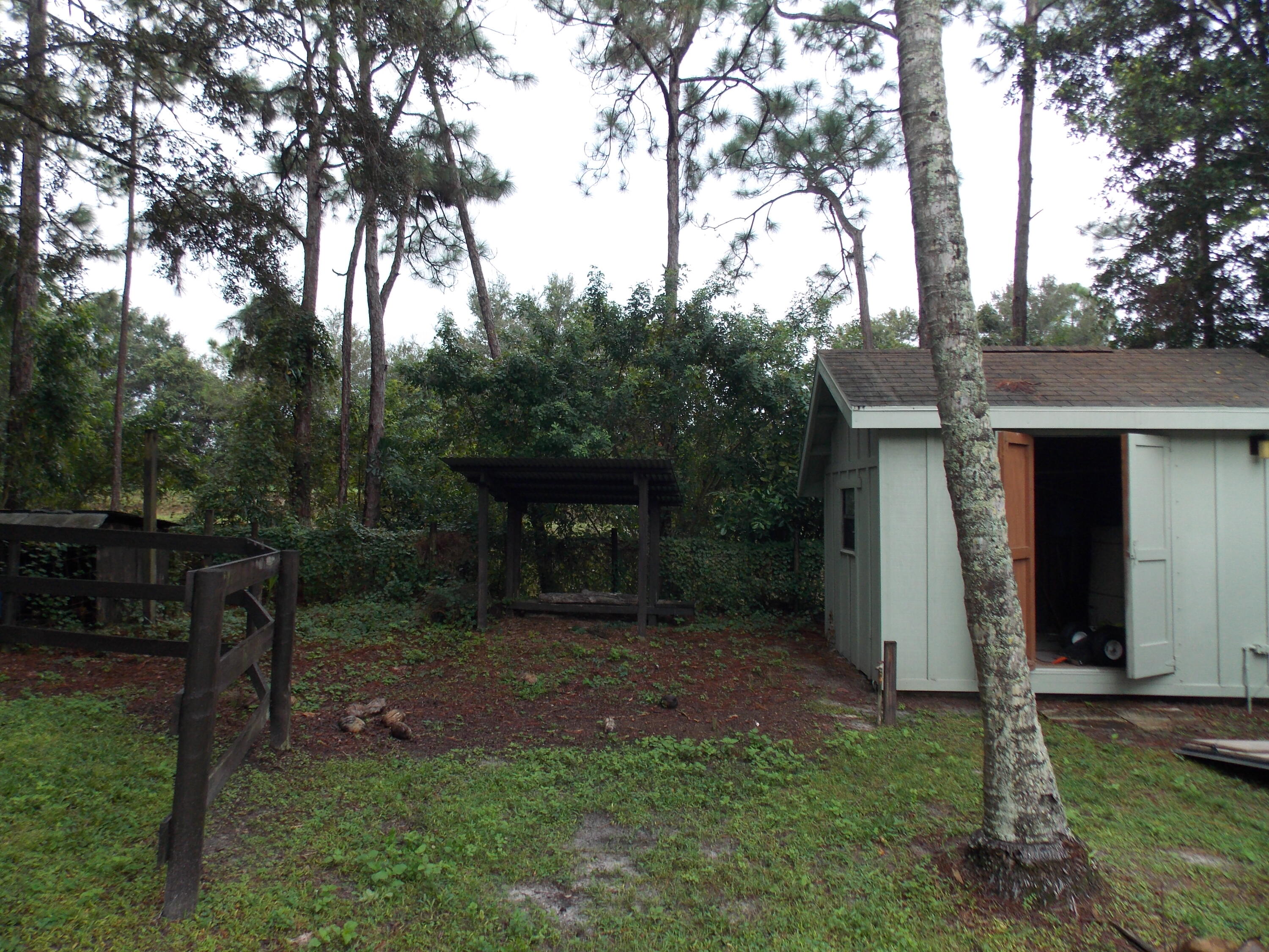16219 134th Terrace North Jupiter, FL 33478 - Photo 39 of 40 a view of a backyard with table and chairs potted plants and large tree