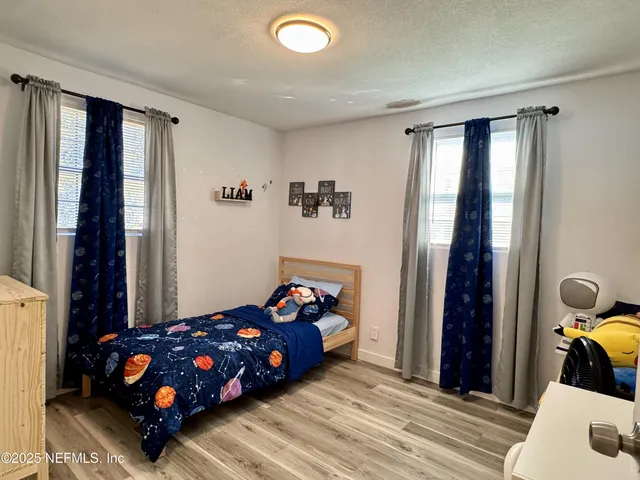 a bedroom with a bed and a dresser with wooden floor