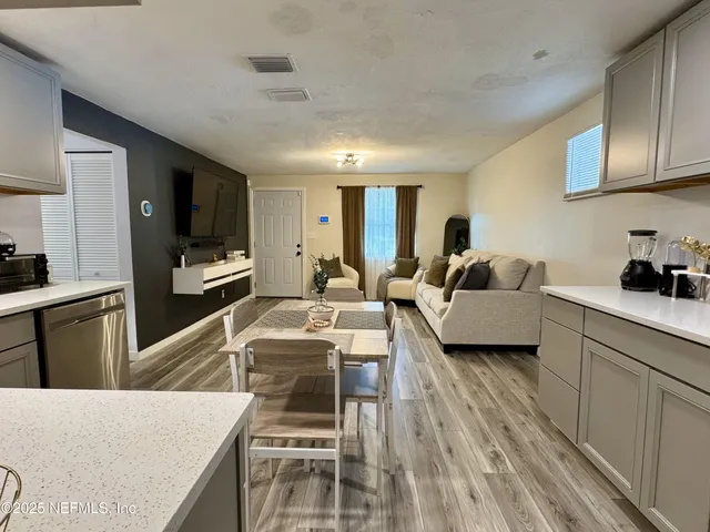 a living room with furniture a flat screen tv and kitchen view