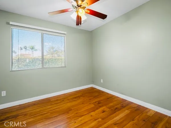 an empty room with wooden floor fan and windows