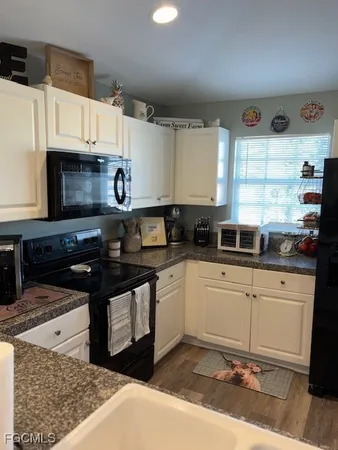 a kitchen with stainless steel appliances granite countertop a kitchen island a stove a sink dishwasher and white cabinets with wooden floor