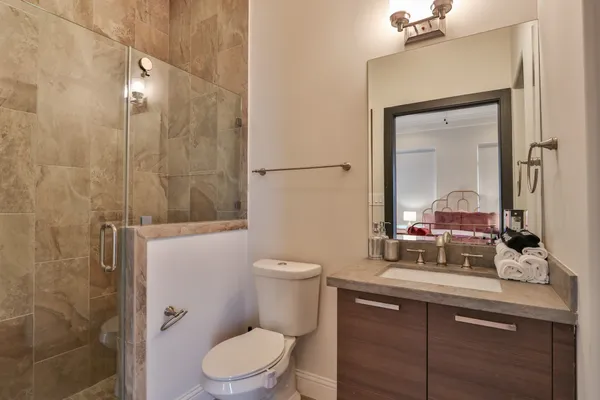 a bathroom with a toilet a sink a mirror a shower and vanity
