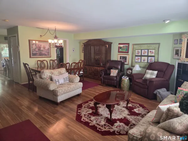 a dining room with wooden floor a chandelier a wooden table and chairs