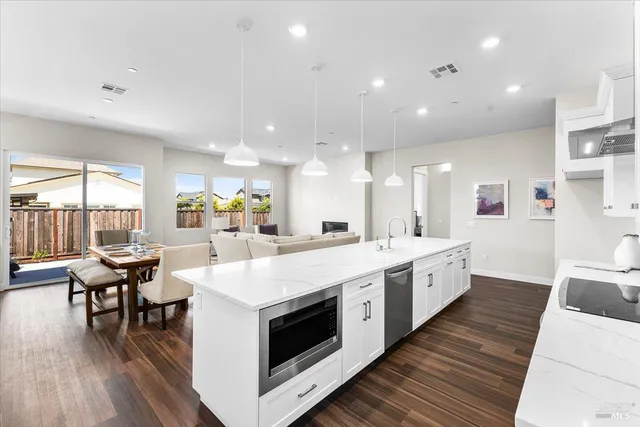 a large white kitchen with stainless steel appliances kitchen island a large counter tops and white cabinets