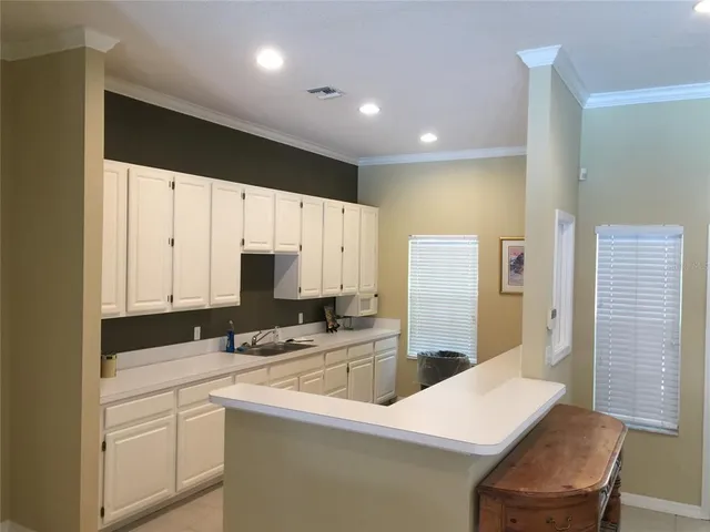 a kitchen with stainless steel appliances a stove a sink a microwave a refrigerator white cabinets and cabinets
