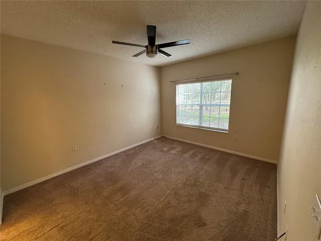 an empty room with a window and a ceiling fan