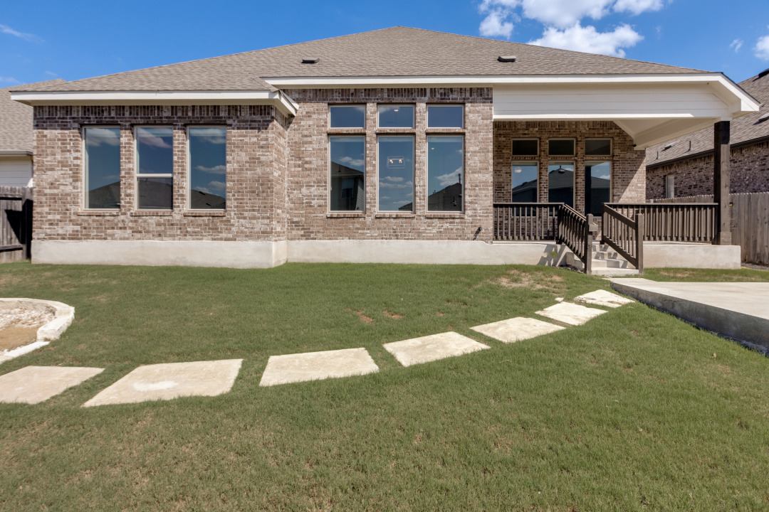 727 Spinnaker Loop Kyle, TX 78640 - Photo 28 of 29 A stone pathway curves across the lawn toward a covered patio and brick exterior.