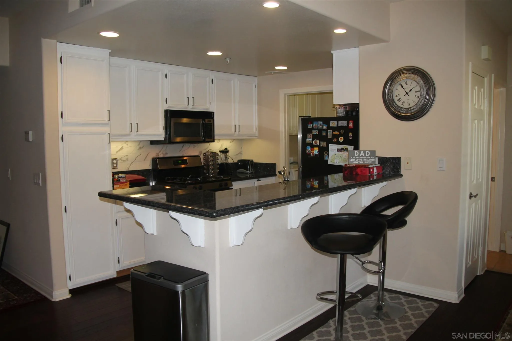 13039 Evening Creek Drive South, Unit 36 San Diego, CA 92128 - Photo 4 of 31 a kitchen with granite countertop a sink a clock and cabinets