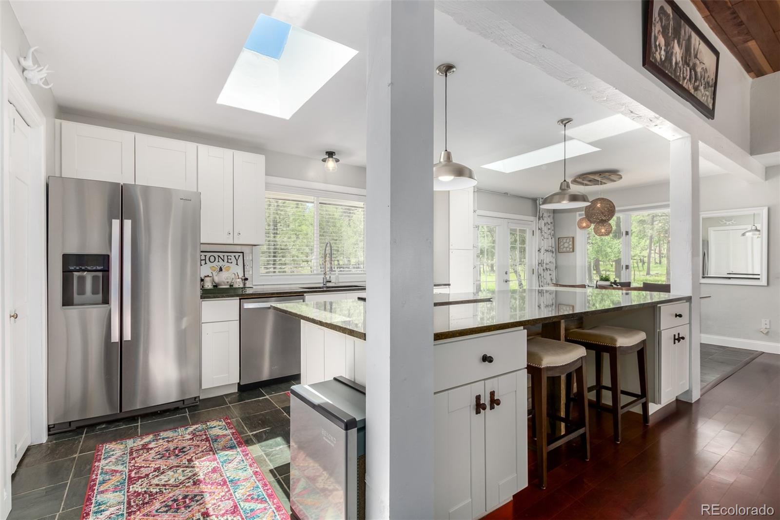 95 Double Tree Road Bailey, CO 80421 - Photo 6 of 40 a kitchen with stainless steel appliances granite countertop a refrigerator a sink dishwasher a stove and white cabinets with wooden floor