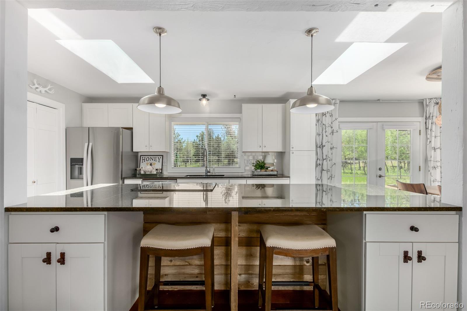 95 Double Tree Road Bailey, CO 80421 - Photo 7 of 40 a kitchen with stainless steel appliances granite countertop a table chairs in it and wooden floors