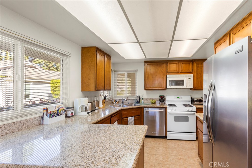 24142 Minnetonka Lane Lake Forest, CA 92630 - Photo 16 of 30 a kitchen with stainless steel appliances granite countertop a sink a stove a refrigerator cabinets and a window