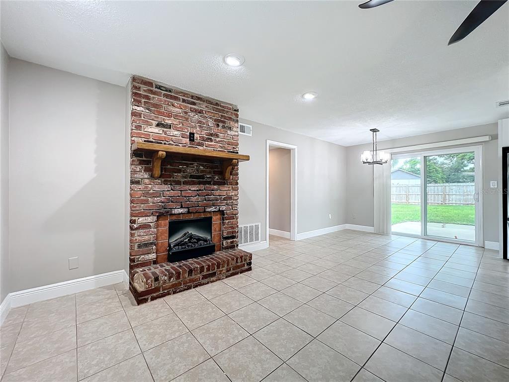 600 Ridgefield Avenue Ocoee, FL 34761 - Photo 14 of 45 Electric Fireplace in living room with ceramic tile floors, upgraded baseboards, new ceiling fan and insulated beveled glass front door opens to dinging area and kitchen.