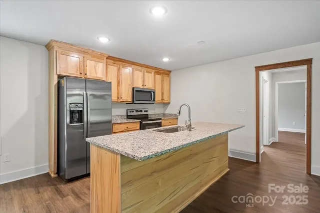 a kitchen with granite countertop kitchen island stainless steel appliances a refrigerator sink stove microwave and cabinets