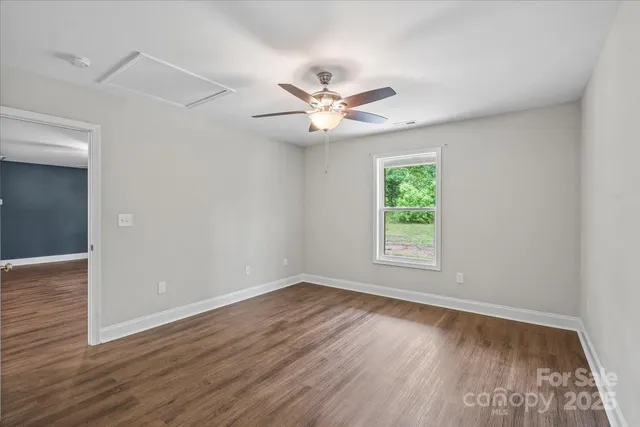 an empty room with wooden floor ceiling fan and window