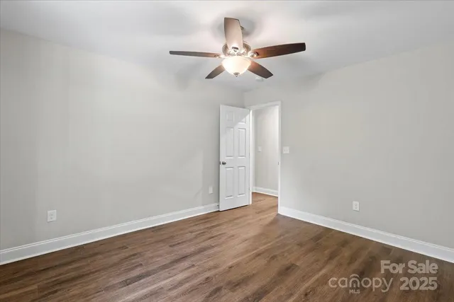 an empty room with wooden floor ceiling fan and window