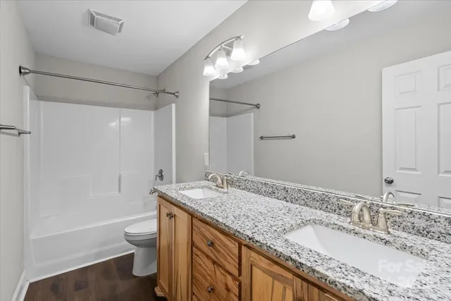 a bathroom with a granite countertop sink a toilet a large mirror and shower