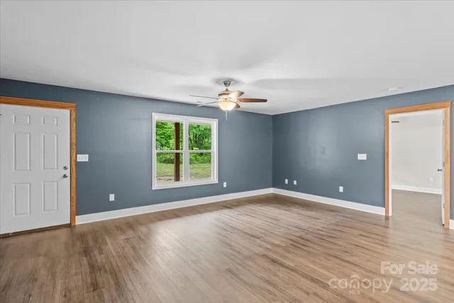 a view of an empty room with window and wooden floor