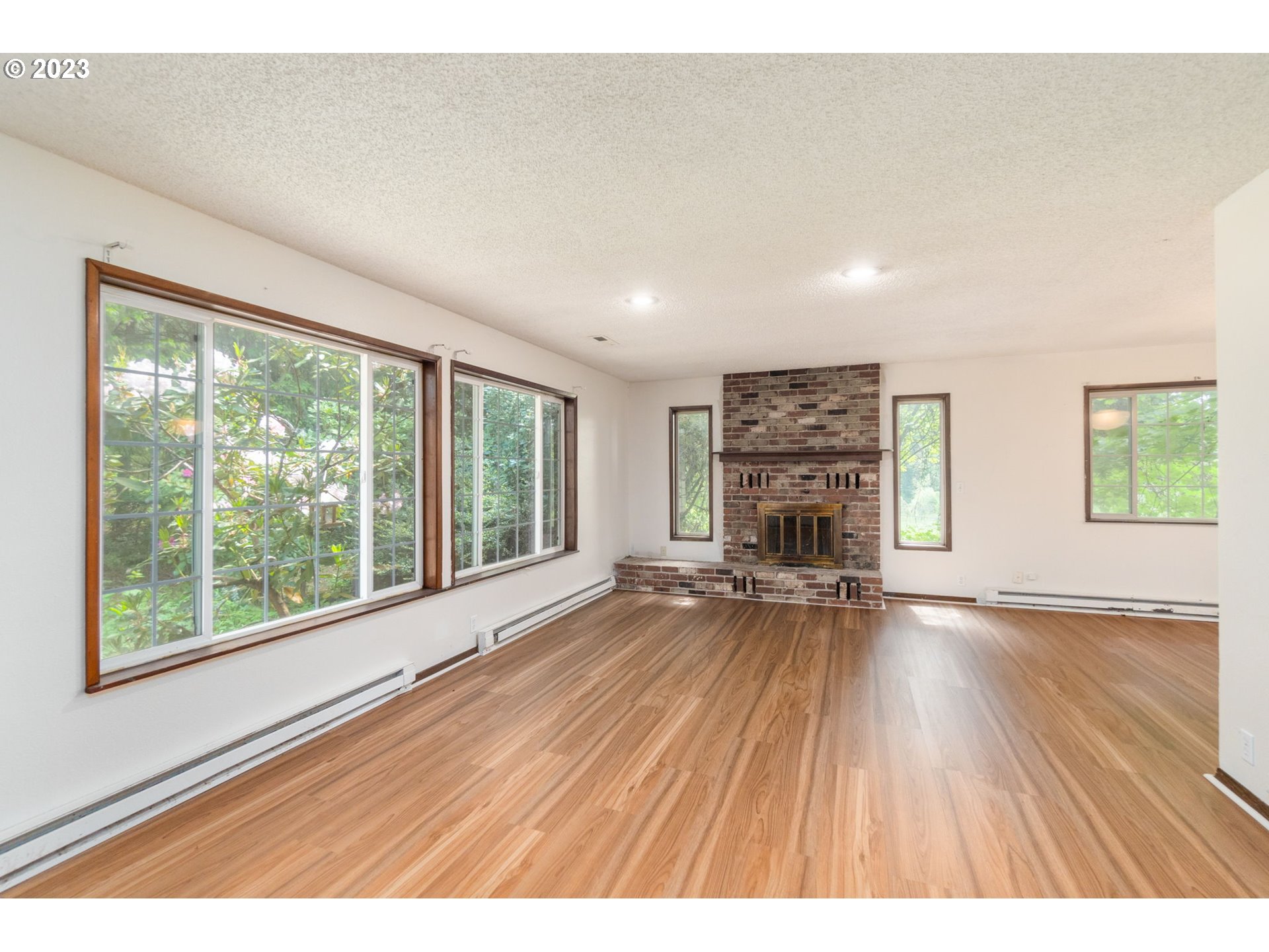 745 Southeast Littlepage Road Corbett, OR 97019 - Photo 4 of 39 a empty room with fireplace wooden floor and windows