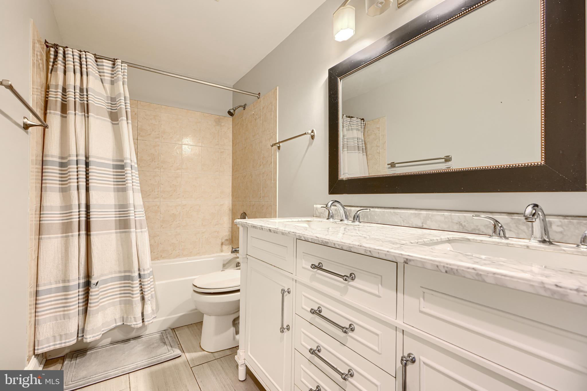 123 West Barre Street, Unit 103 Baltimore, MD 21201 - Photo 21 of 26 a bathroom with a granite countertop sink toilet mirror and a shower