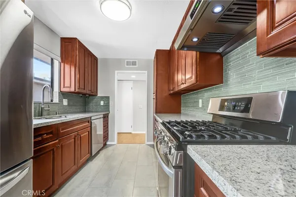 a kitchen with stainless steel appliances granite countertop a stove a sink dishwasher and cabinets with wooden floor