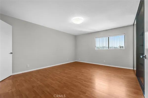 a view of an empty room with a kitchen and entryway with wooden floor