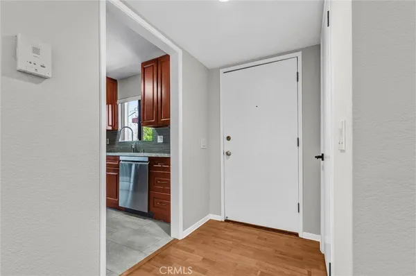 a view of an empty room with kitchen and a window