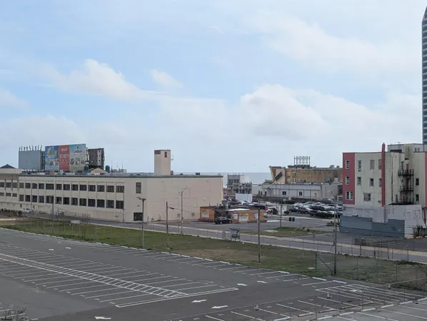 a front view of a building with lot of cars and trees
