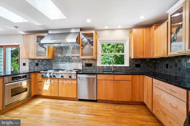 a kitchen with stainless steel appliances granite countertop a stove a sink and a microwave