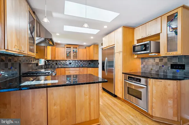 a kitchen with stainless steel appliances granite countertop a stove a sink and a large window with wooden floors