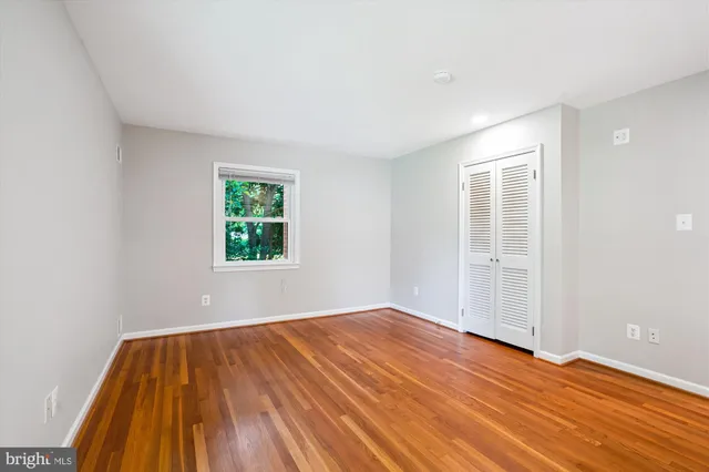a view of an empty room with wooden floor and windows