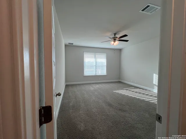 a view of an empty room with a ceiling fan and window