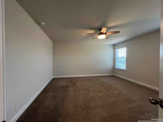 an empty room with closet and a ceiling fan