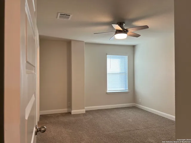 an empty room with a window and a fan