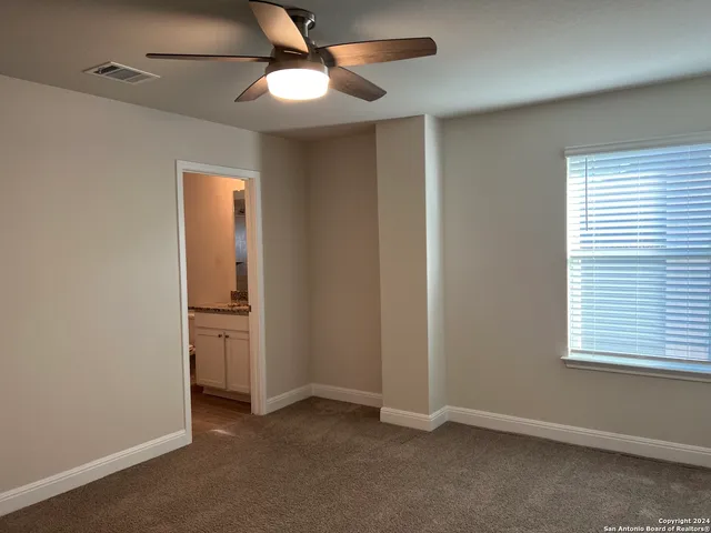 an empty room with windows and fan