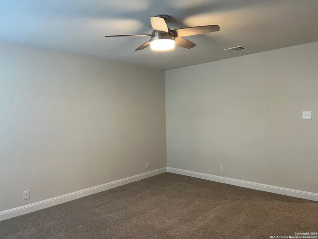 an empty room with a ceiling fan and window