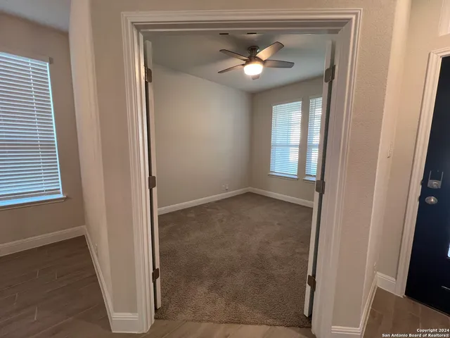 an empty room that has a chandelier fan and a window