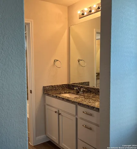 a bathroom with a granite countertop sink and a mirror