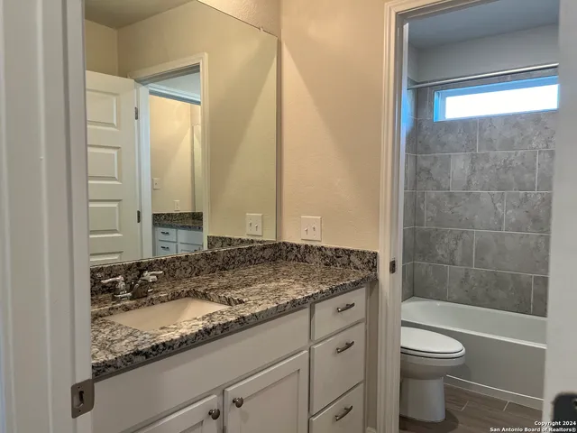 a bathroom with a granite countertop sink toilet and shower