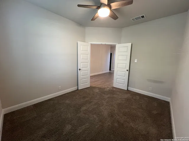 an empty room with closet and a chandelier fan