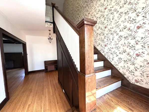 a view of an empty room with wooden floor and fan