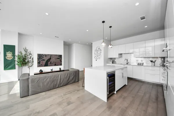a large white kitchen with kitchen island a sink dishwasher stove and white cabinets with wooden floor