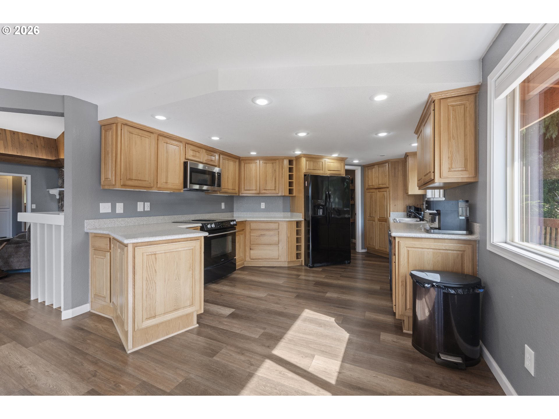 2453 Stephanie Lane North Bend, OR 97459 - Photo 11 of 48 a kitchen with stainless steel appliances kitchen island granite countertop a refrigerator a stove a sink a dining table and chairs with wooden floor