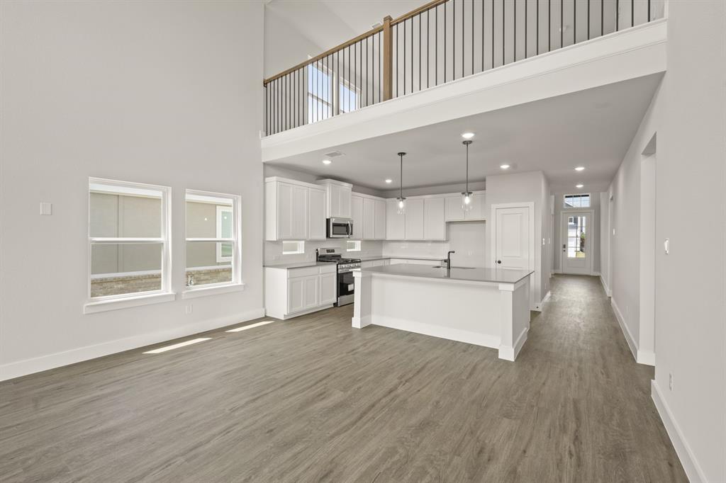 1724 Nesting Robin Lane Krum, TX 76249 - Photo 14 of 40 a large white kitchen with kitchen island a sink wooden floor and a large window