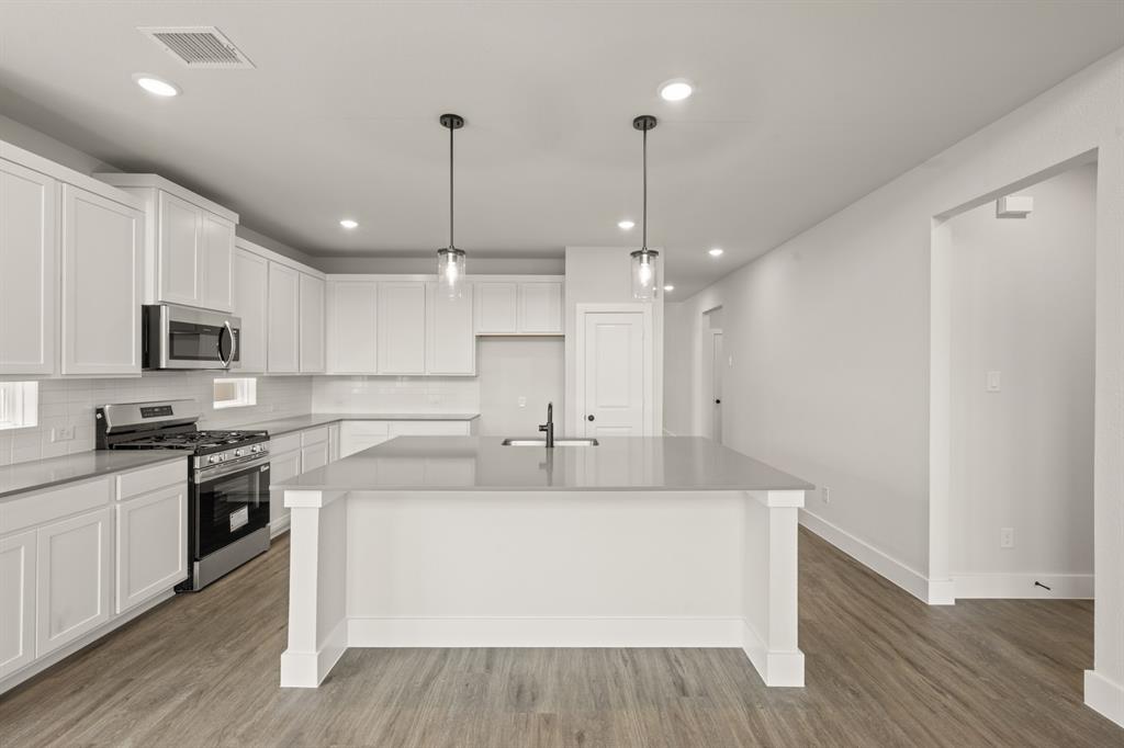 1724 Nesting Robin Lane Krum, TX 76249 - Photo 10 of 40 a large white kitchen with wooden floor and stainless steel appliances